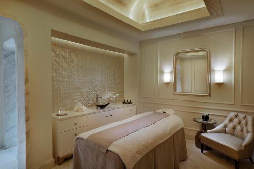 a bedroom with a bed and a mirror and a chair at The St. Regis Abu Dhabi in Abu Dhabi