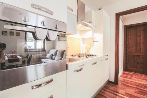 a kitchen with white cabinets and a living room at Appartamento Angelina in Menaggio