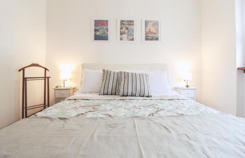 a white bedroom with a large bed with two lamps at Appartamento Angelina in Menaggio