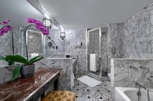 ein Badezimmer mit Marmorwänden, einer Badewanne und einem Waschbecken in der Unterkunft Grand Millennium Kuala Lumpur in Kuala Lumpur