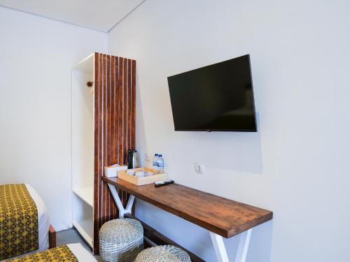 a room with a table with a television on a wall at Cactus Guest House Borobudur in Borobudur