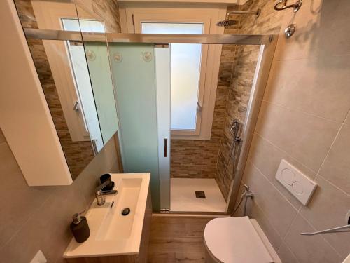 a bathroom with a shower and a toilet and a sink at Condominio Sporting in Lignano Sabbiadoro