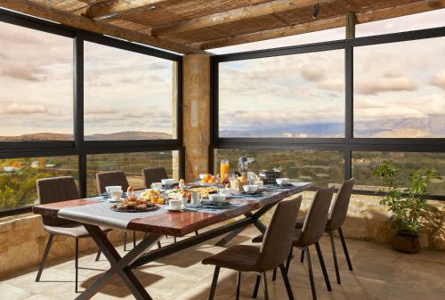 a dining room with a table and chairs and large windows at Alagni Cretan Resort in Alagni
