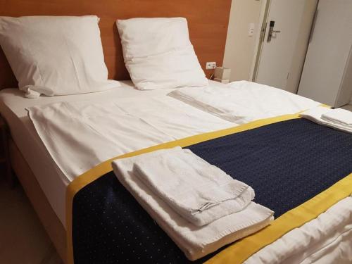 un letto con lenzuola bianche e asciugamani di Hotel Emiliana am Bahnhof a Francoforte sul Meno