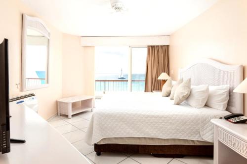 a white bedroom with a bed with a view of the ocean at 2 bedrooms appartement with sea view indoor pool and furnished balcony at Lowlands in Lowlands