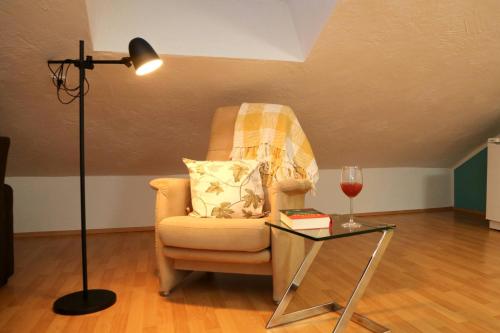 um quarto com uma cadeira, um candeeiro e uma mesa de vidro em Ferienwohnung Vogler em Herscheid