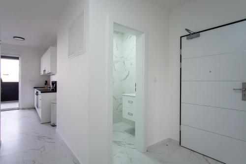 uma casa de banho com paredes brancas e uma porta de duche em vidro. em Noa East Residence em Novalja