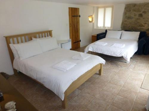 1 Schlafzimmer mit 2 Betten und weißer Bettwäsche in der Unterkunft 15th Century Catalan Farmhouse with pool in Arles-sur-Tech