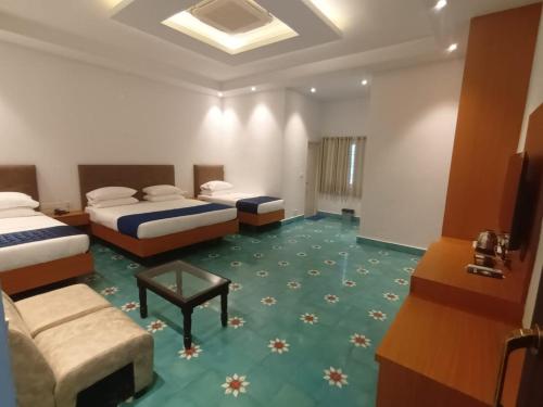 a hotel room with two beds and a table at Nilan Zingle Resort in Puducherry