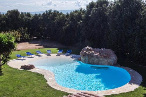 a swimming pool with chairs and a large rock at Agriturismo Villa Gaia in Càbras