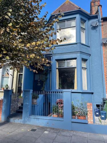 a blue house with a gate in front of it at Cute basement studio in London