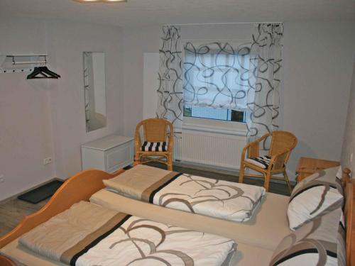 2 łóżka w pokoju z 2 krzesłami i oknem w obiekcie Ferienwohnung Christel w mieście Schmallenberg