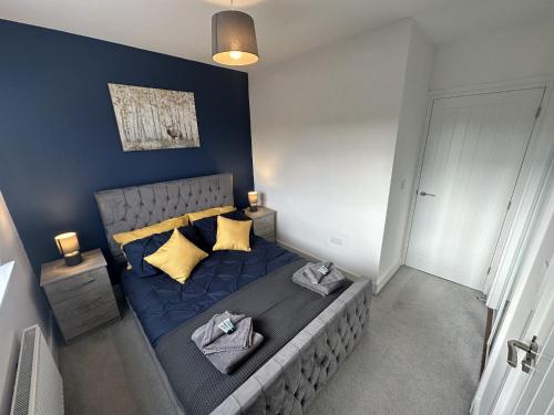 a bedroom with a bed with blue sheets and yellow pillows at 3 Bed Home for Contractors & Relocators with Parking, Garden & WiFi 5 mins walk to Town Centre & Train Station in Stafford