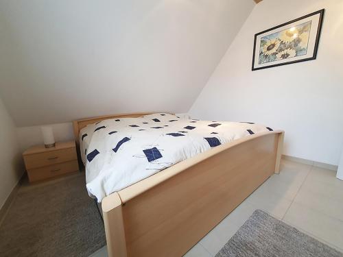 a small bedroom with a bed with a wooden frame at Friesenhain Ferienwohnungen in Sankt Peter-Ording