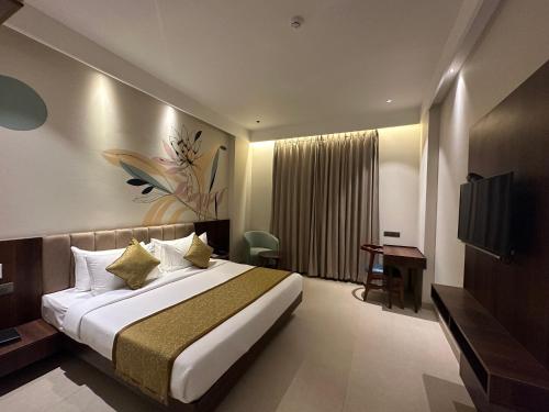 una camera d'albergo con un grande letto e una TV di Hotel Bawa Udaipur a Udaipur