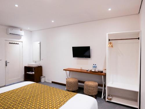 a bedroom with a bed and a desk with a television at Cactus Guest House Borobudur in Borobudur