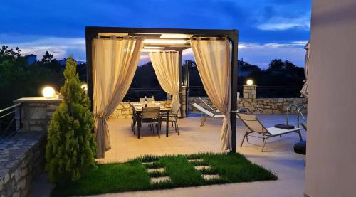 un patio con cenador con mesa y sillas en Natural view villa with private pool, en Skouloúfia