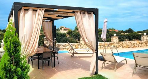 un patio con cenador, mesa y sillas en Natural view villa with private pool, en Skouloúfia