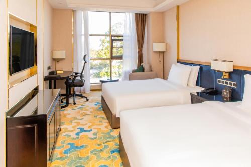 a hotel room with two beds and a flat screen tv at The Venetian Hotel in Lusaka