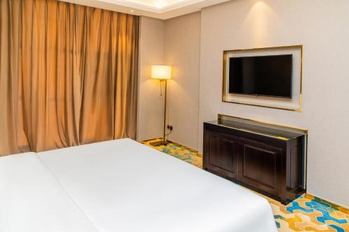 a hotel room with a bed and a flat screen tv at The Venetian Hotel in Lusaka