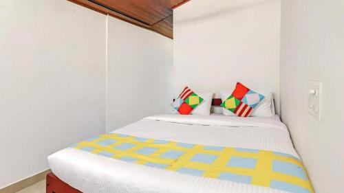 a small white bedroom with a bed with colorful pillows at Westernghats Homestay in Madikeri