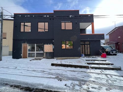 a black house with snow in front of it at THE LOBS, RUSUTSU in Kimobetsu