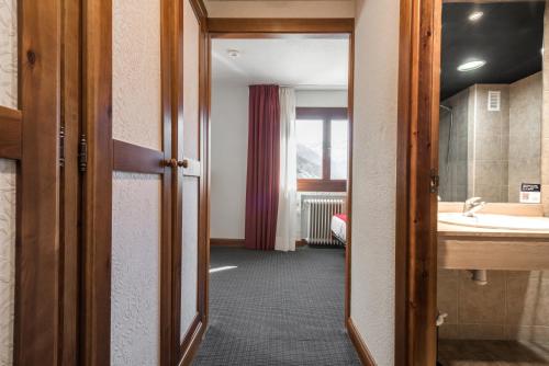 Snö Hotel Formigal في فورميغال: غرفة بحمام مع حوض ومرآة