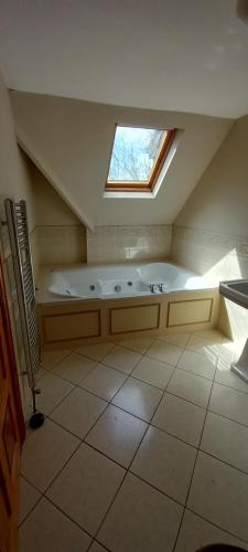 uma casa de banho no sótão com uma grande banheira e uma janela. em Ardsallagh Lodge em Youghal