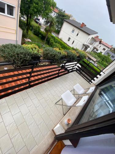 a patio with two white chairs and benches on a balcony at Apartma Magnolija in Nova Gorica