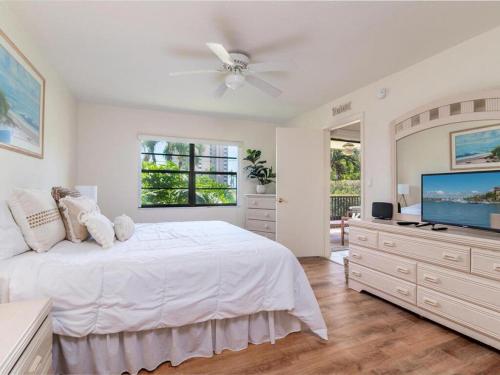 a white bedroom with a large bed and a flat screen tv at Seaview #110 - Just Steps From 1 of 4 Public Beach Access Points in Marco Island