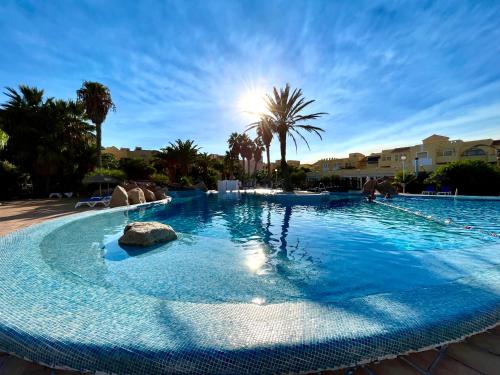 una gran piscina con el sol en el fondo en Apartamentos Moguima, en Roquetas de Mar