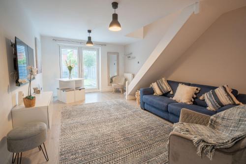 a living room with a blue couch and a staircase at 2 Bed Home - HS2, NEC, Resorts World & BHX Airport in Marston Green