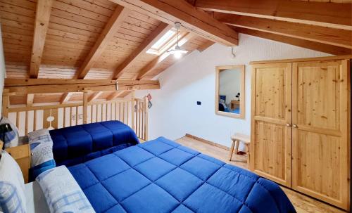 ein Schlafzimmer mit einem blauen Bett und einer Holzdecke in der Unterkunft Appartamento Adamello 15 in Pinzolo
