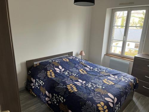 a bedroom with a bed with a blue comforter and a window at 1 appartement neuf centre flers accès facile proche gare et commodités in Flers