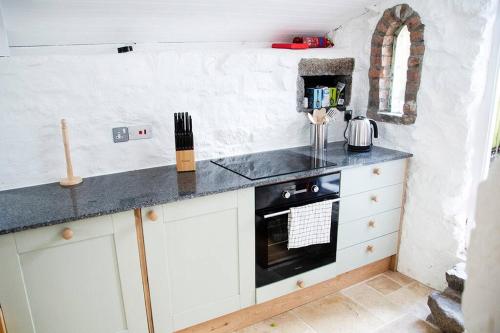 uma cozinha com armários brancos e uma bancada em Lovely cottage with private garden em Penryn