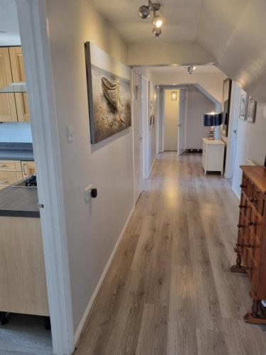 a kitchen and dining room with a hallway with wood floors at Spacious Family Friendly Apartment- 100m from beach with Seaviews! in Hunstanton