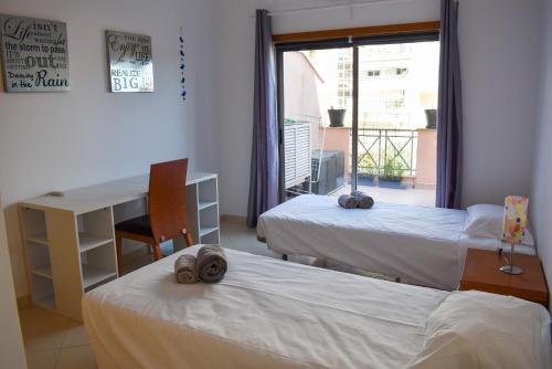 een kamer met 2 bedden, een bureau en een raam bij Apartamento Sol Nascente by Portucasa in Albufeira