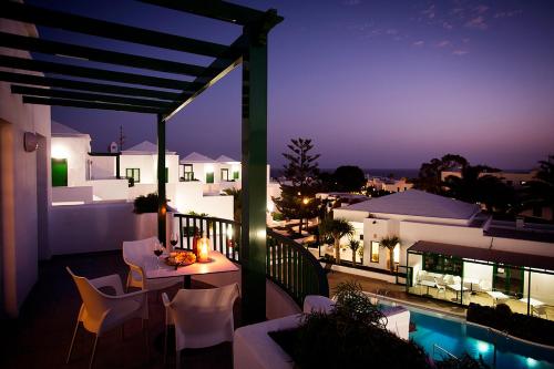 a balcony with a table and chairs and a pool at Apartamentos El Guarapo in Costa Teguise