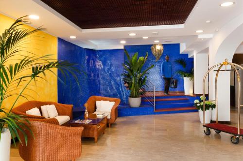 eine Lobby mit Sofas und einem Gemälde eines Mannes in der Unterkunft Hotel Maddalena in Riccione
