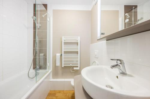 a white bathroom with a sink and a shower at Némo - Appartement avec Terrasse in Courseulles-sur-Mer