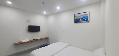 a white room with a bed and a tv at Family Homestay Quy Nhon in Quy Nhon