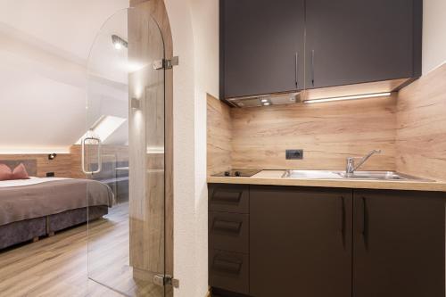 a kitchen with a sink and a bed in a room at Aparthotel Familiaris - Family Apartments - Pools & Spa in Dolomites in Valdaora