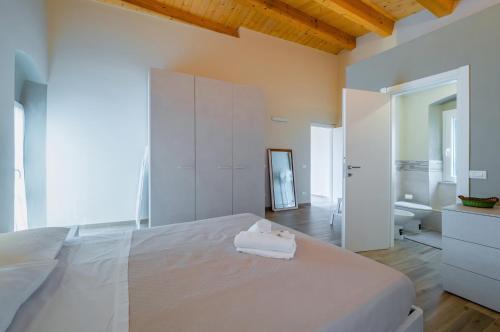 a white bedroom with a large bed and a bathroom at Comfy & Roomy Apt - View on the Ligurian Hills! in Vezzano Ligure