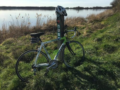 a bike parked next to a pole next to a lake at Roue d'escampette Gîte d'étape et de séjour in Champagnat
