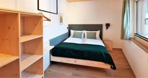 a bedroom with a bed with a green blanket at vomLandl Natur Lofts & Apartments Leogang in Leogang