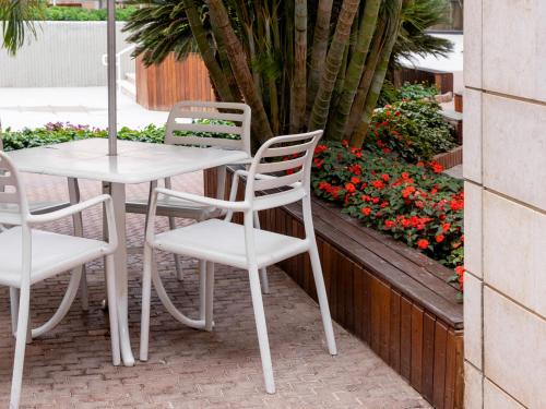 a white table and chairs on a patio with flowers at Riviera by Isrotel Collection in Eilat