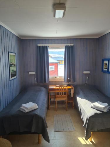 a room with two beds and a table and a window at Berlevåg Motell AS in Berlevåg