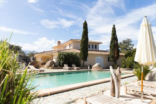 uma piscina em frente a uma casa com um guarda-chuva em Corsicatours Villa em Porto-Vecchio