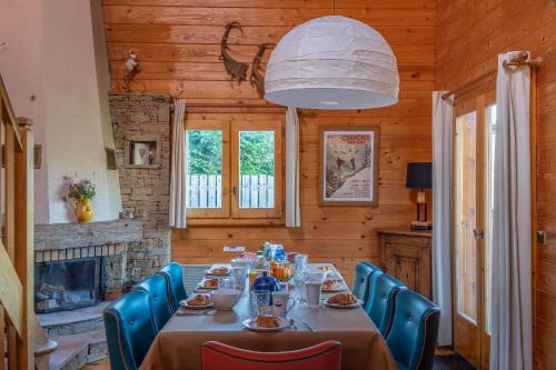 une salle à manger avec une table, des chaises et une cheminée dans l'établissement Chalet Mahana, aux Gets