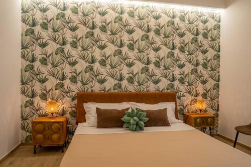 um quarto com uma cama e uma parede com um papel de parede frondoso em Le Camere della Scala em Porto Empedocle